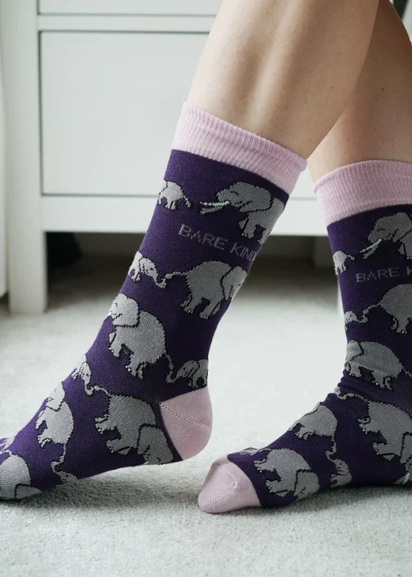 The legs of a person wearing Bare Kind's Save the Elephant purple, pink & grey bamboo socks