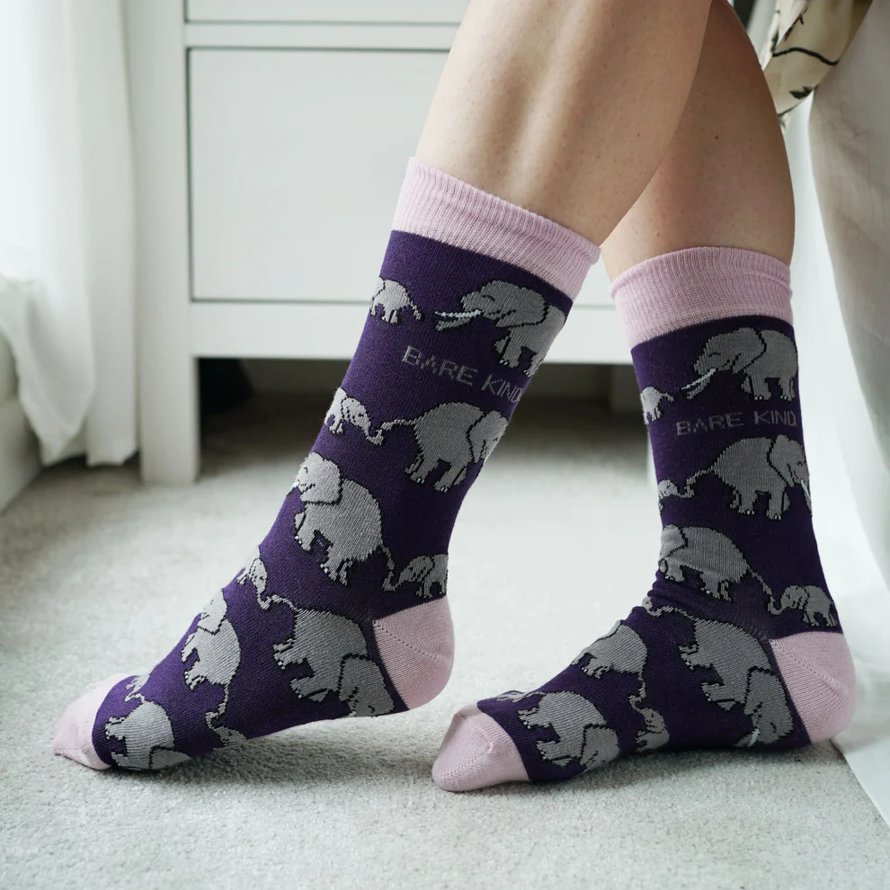 The legs of a person wearing Bare Kind's Save the Elephant purple, pink & grey bamboo socks